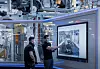 Zwei Produktionsmitarbeiter von Mercedes-Benz stehen im Werk Bremen vor einem großen Informationsbildschirm