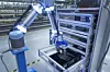 Ein Roboter-Greifarm im BMW Werk greift mit KI verschiedene Teile.