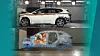 SUV in Crashtest-Halle mit darunterliegender blauer Simulationsgrafik des Innenraums