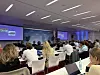 Großaufnahme des Konferenzsaals der CMxC 2026 Corporate Mobility Conference im Hochhaus des Süddeutschen Verlags in München mit Publikum von hinten, voll besetzten Tischreihen, Bühne, Referent am Rednerpult, Präsentationsfolien auf zwei großen Leinwänden, Ultimamedia- und Süddeutscher-Verlag-Branding im Hintergrund, Fachkonferenz zu Corporate Mobility, Fuhrparkmanagement, Elektromobilität, Digitalisierung, Nachhaltigkeit, Mobilitätsmanagement, Flottenstrategie, CO₂-Reduktion, Kostenkontrolle, Mitarbeiter-Mobilität und Zukunft der Unternehmensmobilität mit Fachpublikum aus Fuhrpark, HR, IT, Finance und Einkauf