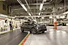 Volvo EX60 electric SUV on an illuminated assembly line inside a factory.