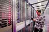 Techniker steht mit einem mobilen Gerät zwischen Serverracks in einem Rechenzentrum von 1&1 in Baden. Die Aufnahme zeigt Reihen von Servern mit roten und blauen Statusleuchten und verweist auf den Ausbau deutscher Cloud-Infrastruktur.