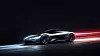 Extrem minimalistisches KI-Bild eines generischen futuristischen Autos ohne Markenlogo, das mit hoher Geschwindigkeit durch eine dunkle, reduzierte Umgebung fährt. Das silberne Konzeptfahrzeug mit flacher, aerodynamischer Karosserie, schmalen Lichtsignaturen und großen Rädern wird von blauen und roten Lichtspuren begleitet, die Dynamik, Beschleunigung und technologische Zukunft vermitteln. Das Motiv steht symbolisch für softwaredefinierte Fahrzeuge, schnelle Lernzyklen, künstliche Intelligenz, Kundendaten, kontinuierliche Software-Updates und den zunehmenden Wettbewerb der Automobilhersteller um Geschwindigkeit, Innovationsfähigkeit und bessere Nutzererlebnisse.