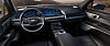 Innenraum eines Cadillac mit großflächigem Digitaldisplay, Infotainmentsystem, Lenkrad und Touchscreen in der Mittelkonsole.