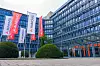 Glasfassade eines Bürogebäudes mit mehreren Aumovio-Flaggen im Vordergrund.