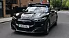 Schwarzer Ford Mustang Mach-E mit Sensoraufbau für automatisiertes Fahren auf einer Londoner Wohnstraße.