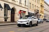 Weißes Robotaxi mit Sensoraufbau fährt durch eine innerstädtische Straße in Zagreb.