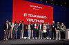 Gruppenfoto der Gewinnerinnen und Gewinner  der automotiveIT IT Team Awards 2025 auf der Bühne vor einer roten Award-Leinwand.