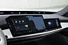 Innenraum eines BMW 7er mit großem zentralen Infotainment-Display und separatem Bildschirm auf der Beifahrerseite. Die Anzeige zeigt unter anderem Navigation, Mediensteuerung, Wetterinformationen und weitere digitale Fahrzeugfunktionen.