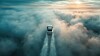 Ein Auto fährt auf einer Spur durch dichte Wolken unter einem hellen Himmel.