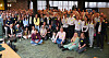 Eine große Gruppe von Menschen steht und sitzt in einem Konferenzraum für ein Gruppenfoto.