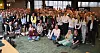 Eine große Gruppe von Menschen steht und sitzt in einem Konferenzraum für ein Gruppenfoto.