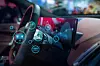 Innenraum eines vernetzten Fahrzeugs mit Lenkrad und großem Infotainment-Display, überlagert von digitalen Symbolen für Fahrzeugdaten, Vernetzung und Energie.