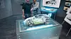 Zwei Männer sehen sich ein Hologramm eines Autos auf einem Displaytisch an.