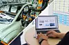 Geteiltes Bild mit einer Karosserie in der Automobilproduktion auf der linken und einem Arbeitsplatz mit Laptop auf der rechten Seite. Es symbolisiert den Wechsel von der Fertigung in die IT.