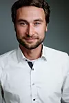 Porträt eines Mannes mit weißem Hemd vor grauem Hintergrund. Peter Sorowka, Cybus