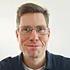 Nahaufnahme eines Mannes mit Brille vor hellem Hintergrund. Willem Grobler, V4Smart