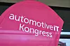 Pinkes Banner mit der Aufschrift „automotiveIT Kongress“ in einem Innenraum.