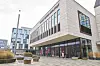 Modernes Gebäude mit Glasfront, gepflastertem Vorplatz und runden Sitzbänken im Außenbereich.