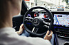 Blick aus dem Fond auf ein Mercedes-Benz-Lenkrad, digitales Cockpit und Navigationsbildschirm im Stadtverkehr.