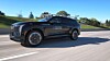Ein schwarzer SUV der Marke Cadillac fährt auf einer Autobahn bei sonnigem Wetter.