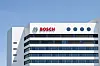 Außenansicht eines modernen Bosch-Gebäudes mit weißer Fassade, dunklen Fensterbändern und blauem Himmel im Hintergrund. Im oberen Bereich der Front ist das Bosch-Logo in Rot zusammen mit dem runden Markensymbol angebracht. Das Bild steht für die angekündigte Neuordnung der Bosch-Konzernstruktur in Deutschland, bei der der Bereich Mobility sowie Bosch Digital, Global Business Services und Bosch Real Estate bis 2027 als eigenständige Tochtergesellschaften innerhalb der Bosch-Gruppe aufgestellt werden sollen.