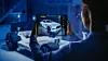 Eine Frau betrachtet auf einem Tablet ein digitales 3D-Modell eines Autos. Im Hintergrund ist ein Fahrzeugchassis in einer blau beleuchteten Entwicklungsumgebung zu sehen.