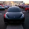 Tesla Model 3 auf einem Parkplatz mit Ladesäulen von Tesla.