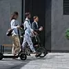 Two colleagues going downtown street talking. Shared eco-friendly transportation
