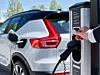 Volvo-Fahrer hält Ladeschlüssel an eine Ladestation.