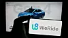 Stuttgart, Germany - 01-23-2025: Person holding mobile phone with logo of Chinese autonomous driving company WeRide Inc. on screen in front of web page. Focus on phone display.