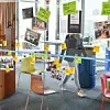Eine Glaswand mit vielen bunten Post-it-Zetteln im SDC von Audi in Ingolstadt. Im Hintergrund geht eine Person vorbei.