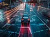 A self-driving car equipped with sensors autonomously drives down a city street illuminated by the glow of urban lights at night