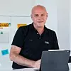 Audi-CIO Frank Loydl hinter einem Laptop am Schreibtisch.