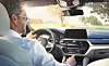 Der Fahrer eines BMWs nutzt die Sprachsteuerung seines Infotainment-Systems.