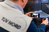 Ein Mann vom TÜV Nord untersucht ein Fahrzeug via Smartphone