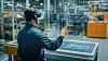 Automotive engineer wearing augmented reality headset interacting with plans in futuristic factory