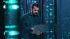 Mann mit Laptop in einem Serverraum