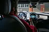 Ein mann sitzt am Steuer eines Mini und schaut auf sein Smartühone