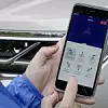 Frau hält Mobiltelefon mit Park Assist-App von VW.