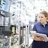 Mitarbeiterin mit Tablet steht an einer Industrieanlage in einem Werk von Bosch