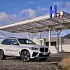 Der BMW iX5 Hydrogen steht vor einer Wasserstoff-Tankstelle. Das Pilotfahrzeug mit Brennstoffzelle könnte der Technologie einen Schub verleihen.